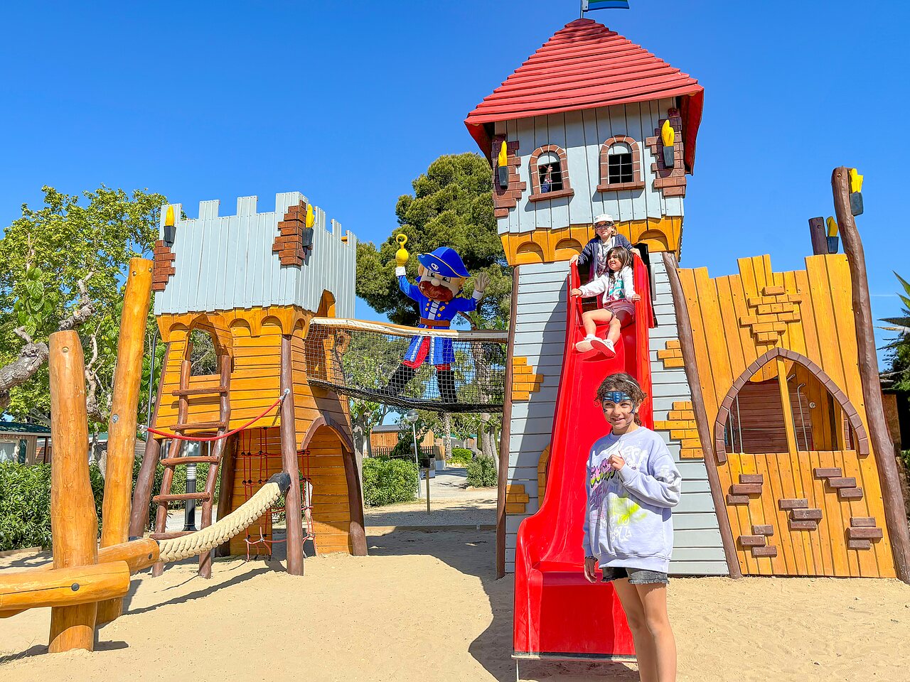 Aire de jeux ch�teau avec toboggan et enfants souriants au camping CAPFUN Alba � CREIXELL (43).