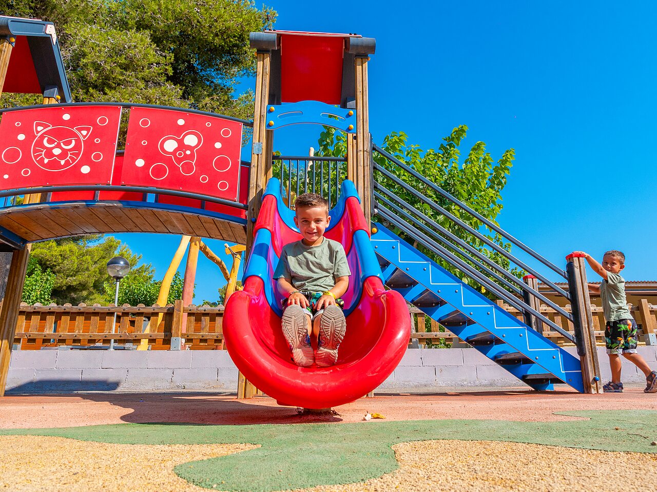Enfants sur l'aire de jeux avec toboggan au camping CAPFUN Alba � CREIXELL (43).