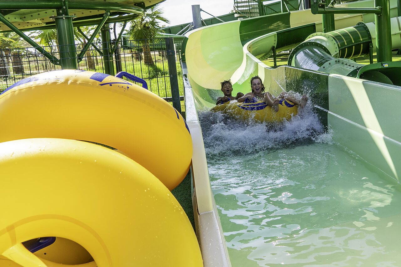 Enfants sur toboggan aquatique avec bou�e au camping CAPFUN Aube � Deltebre, Tarragone.