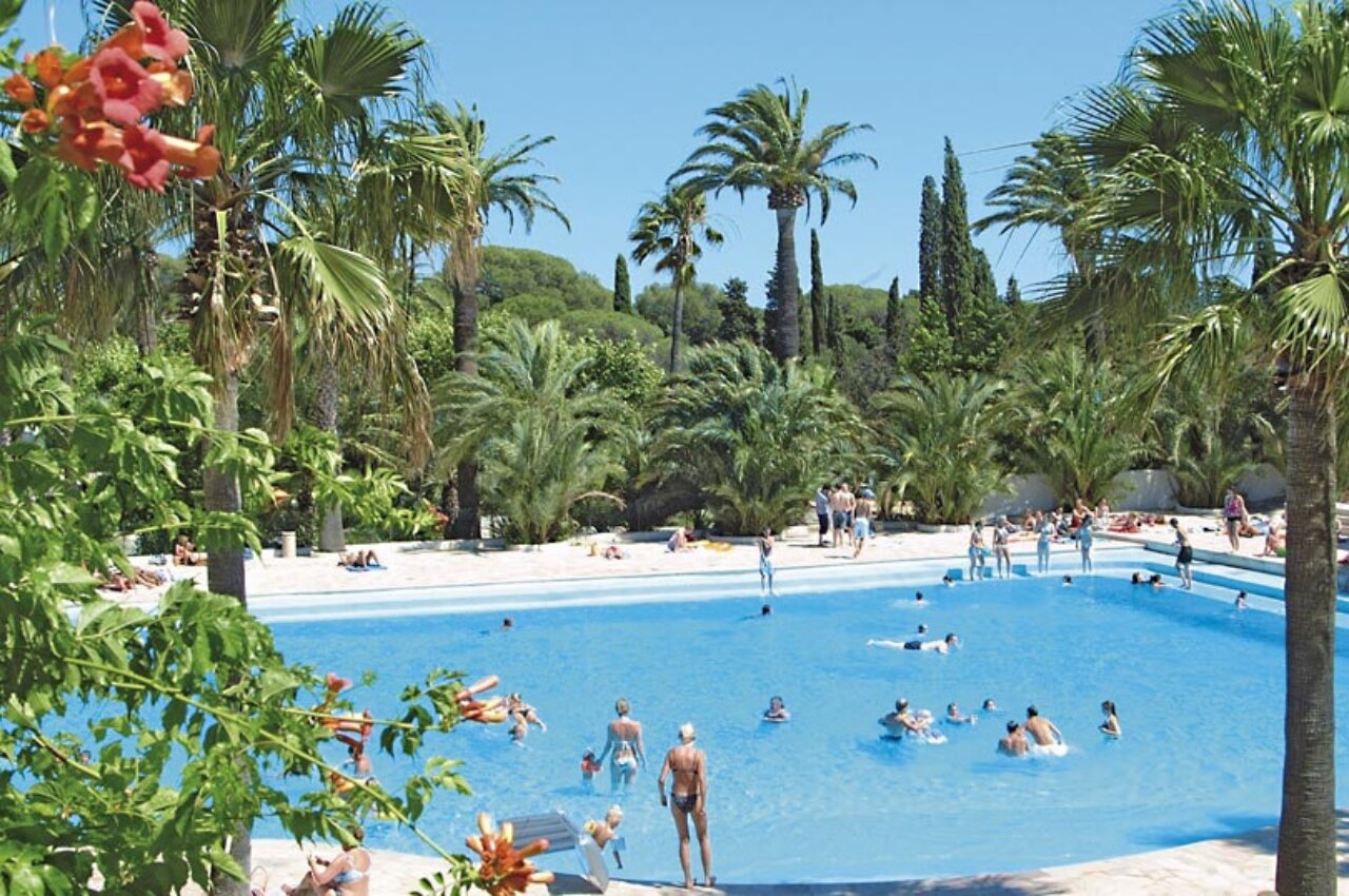 Piscine ext�rieure lagon avec palmiers et baigneurs au camping CAPFUN La Baume - La Palmeraie � Fr�jus (83).