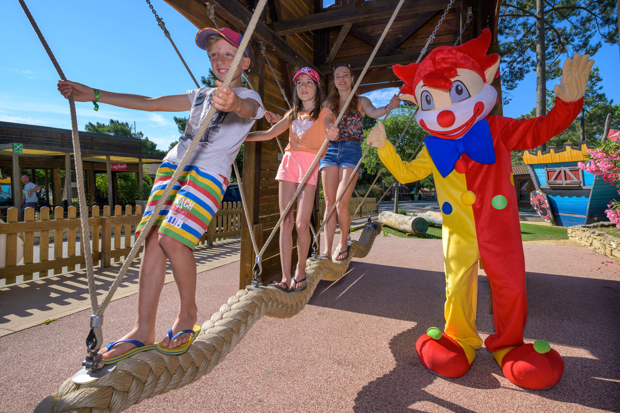 Enfants jouant sur un pont de cordes avec mascotte au camping CAPFUN Beauregard � MORNAS (84).