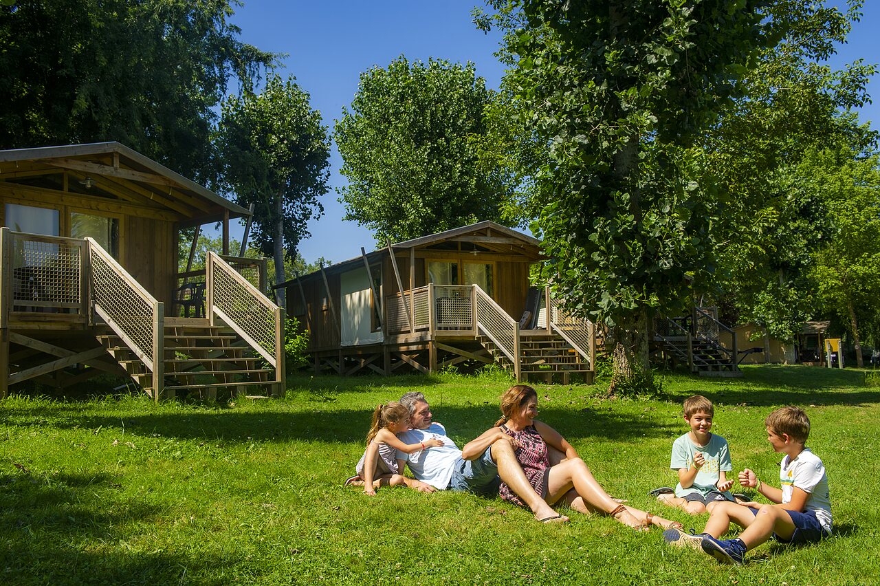 Famille d�tendue devant Mobil-homes en bois au camping CLICOCHIC Beau Rivage � LA ROQUE-GAGEAC.