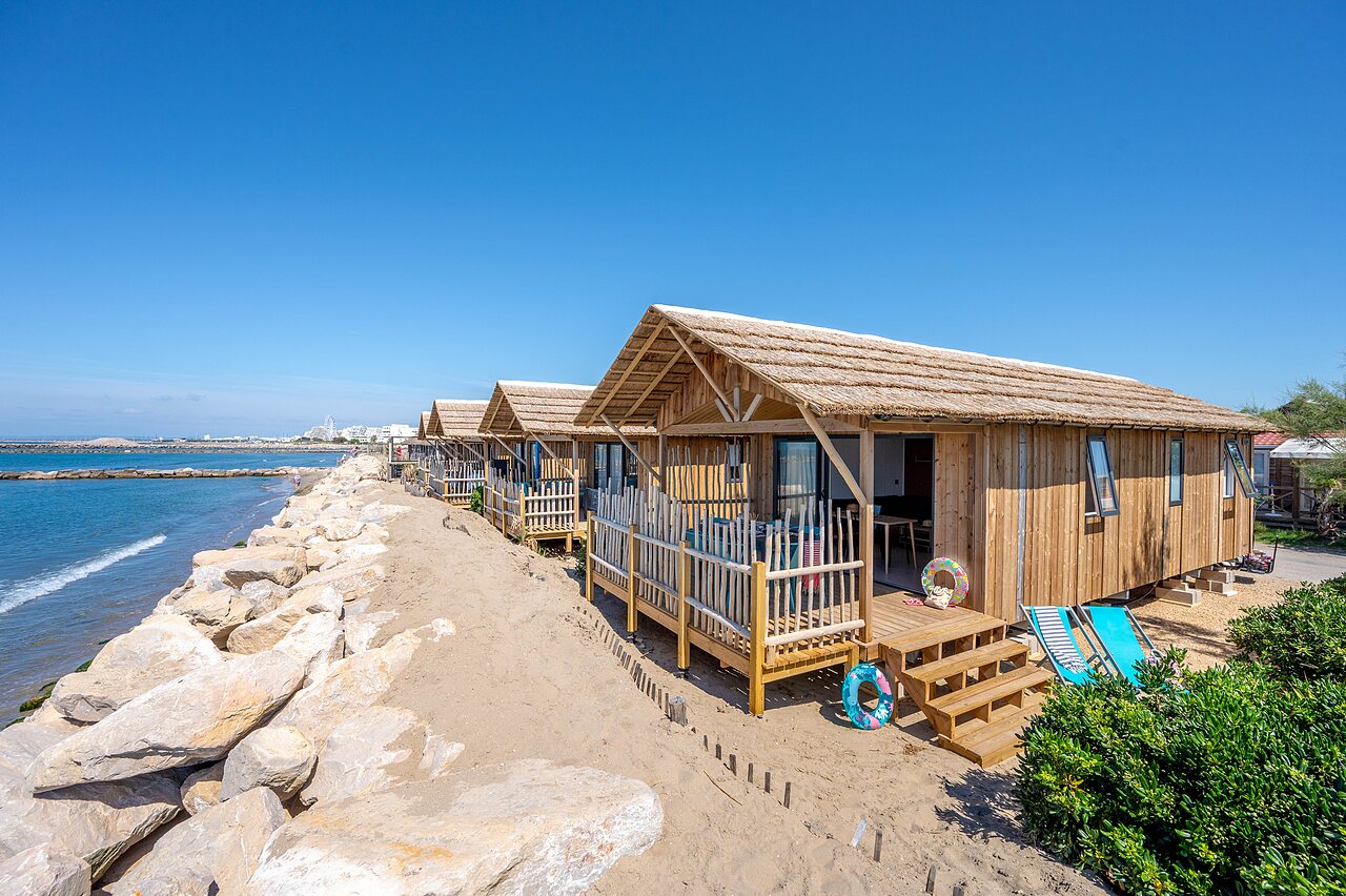 Chalets en bois avec toits de chaume sur la plage au camping CAPFUN Boucanet � LE GRAU DU ROI (30).
