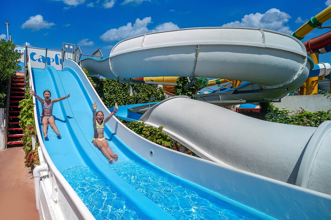 Enfants joyeux sur toboggan aquatique bleu au camping CAPFUN Boucanet � LE GRAU DU ROI (30).