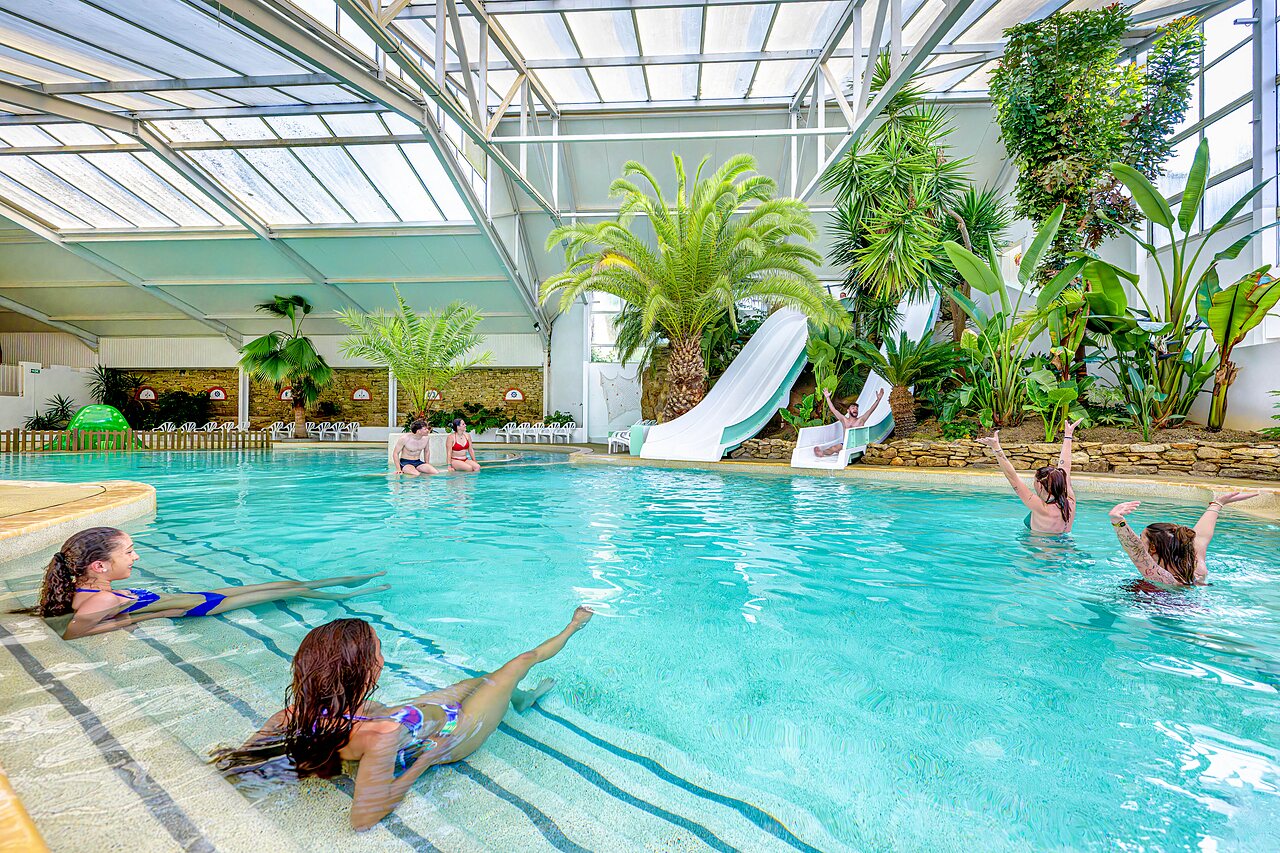 Piscine couverte avec toboggans et palmiers au camping CAPFUN Cenic � PENESTIN (56).