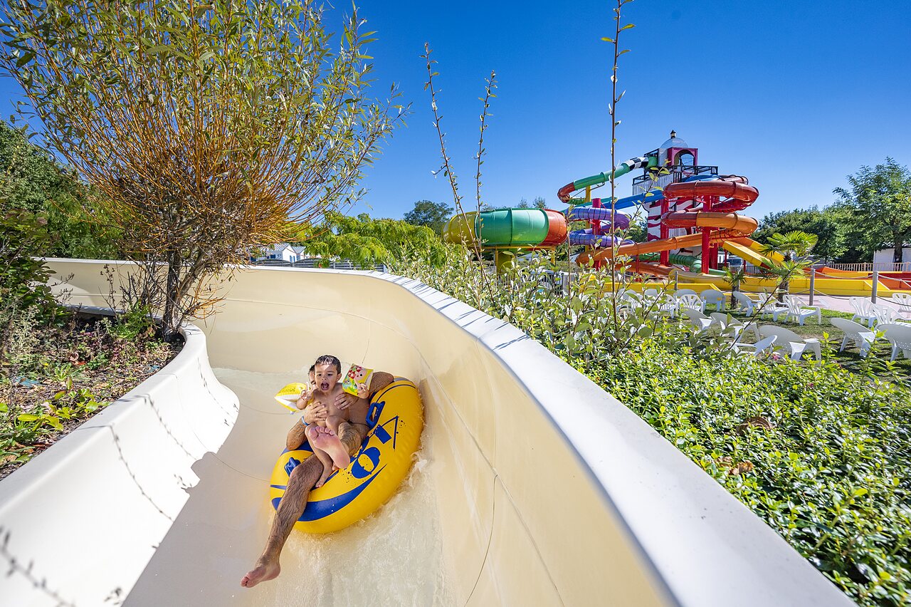 Enfant et adulte sur bou�e dans toboggan aquatique au camping CAPFUN Cenic � PENESTIN (56).