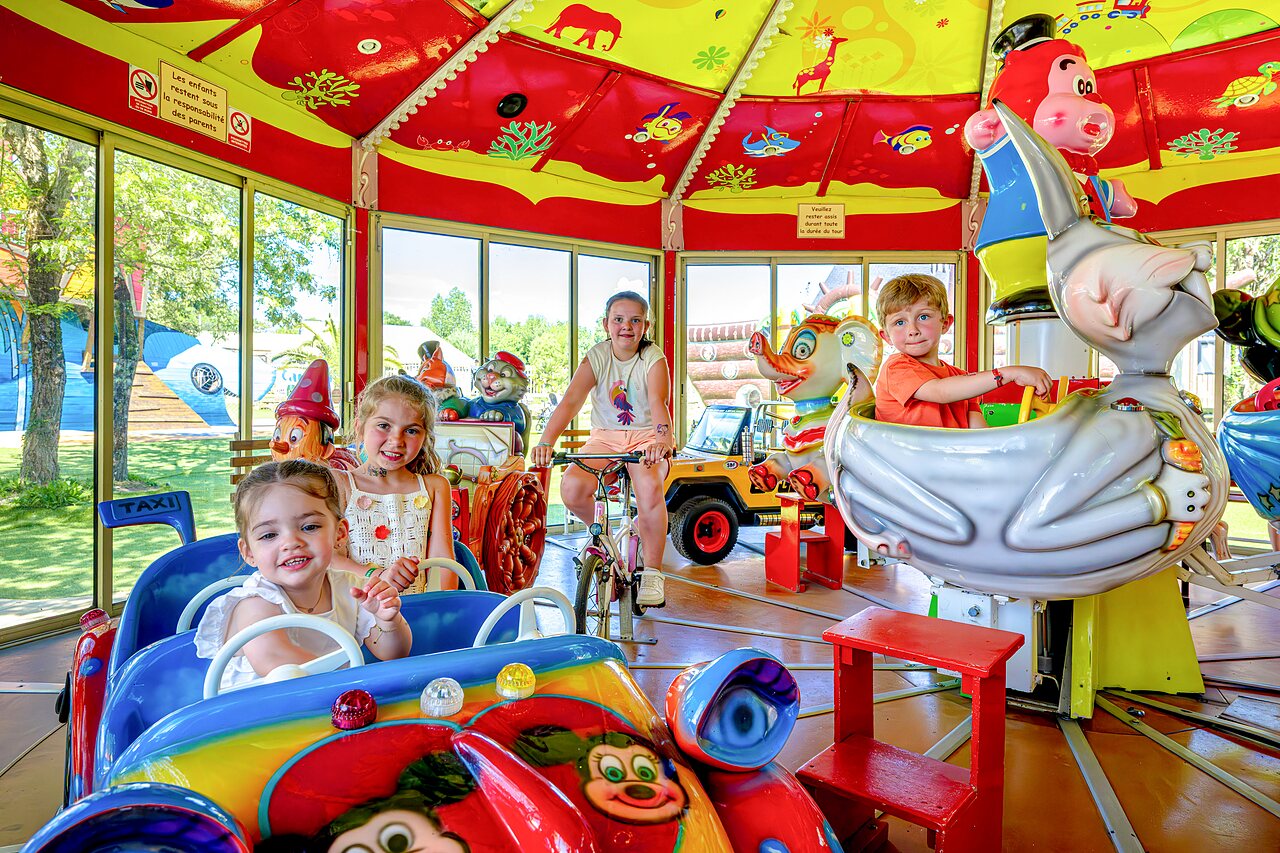 Carrousel color� avec enfants, aire de jeux int�rieure au camping CAPFUN Cenic � PENESTIN (56).