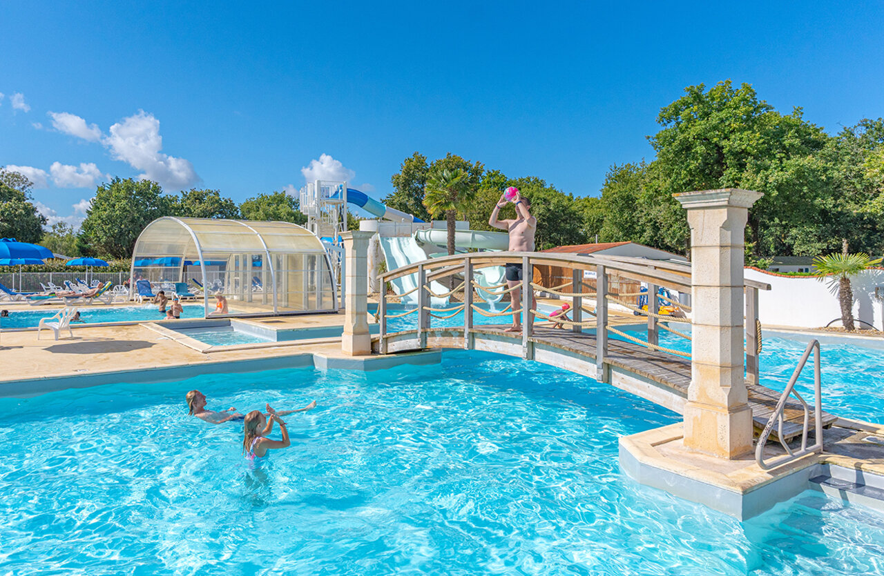 Piscine ext�rieure, toboggans et pont d�coratif au camping VAGUES OCEANES Domaine les Charmilles � Saint-Laurent-de-la-Pr�e (17).