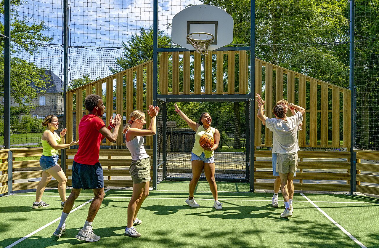 Jeunes jouant au basketball sur le terrain multisport du camping CAPFUN Ch�teau de Galin�e.