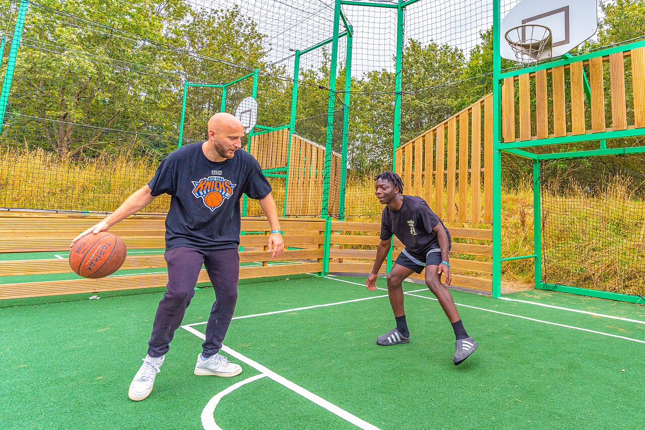 Deux hommes jouent au basketball sur terrain multisport au camping CAPFUN La Ch�naie � PORNIC (44).