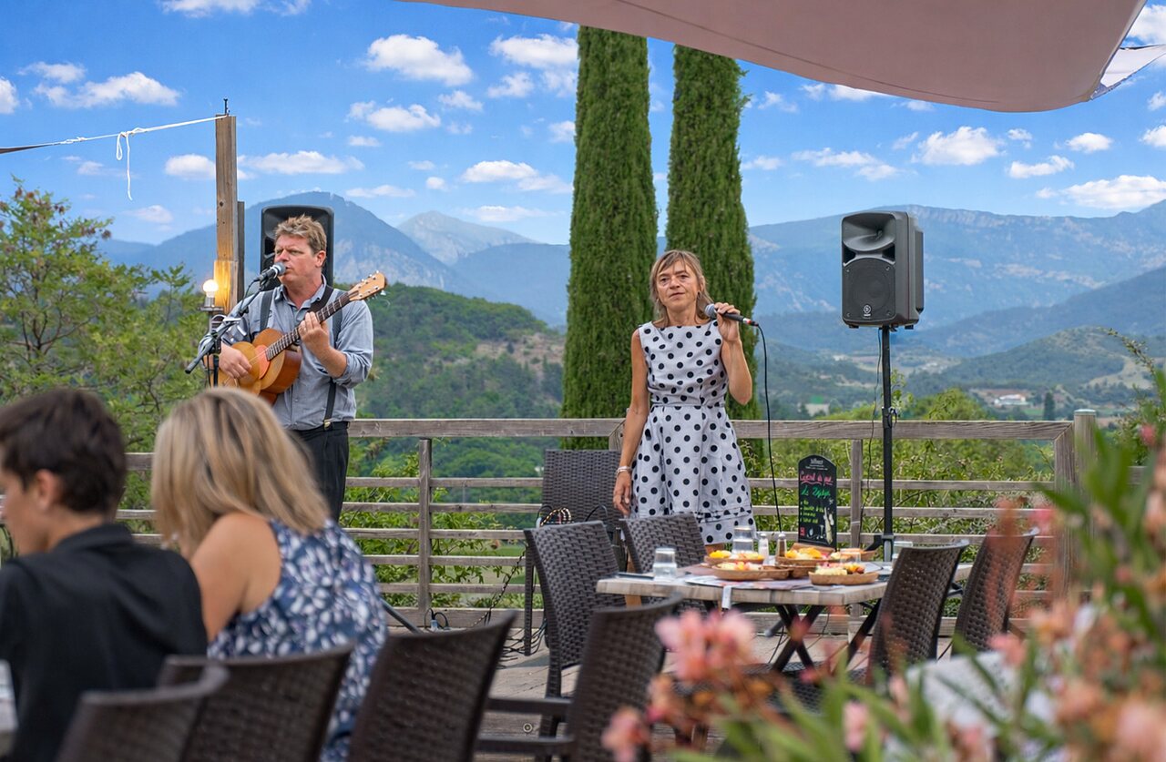Concert live avec chanteuse et guitariste au restaurant du camping CLICOCHIC Couriou.