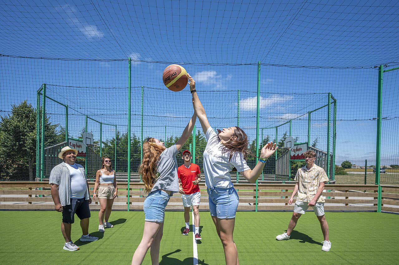 Deux jeunes femmes jouent au basketball sur terrain multisport au camping CAPFUN Curty's � Jard sur Mer (85).