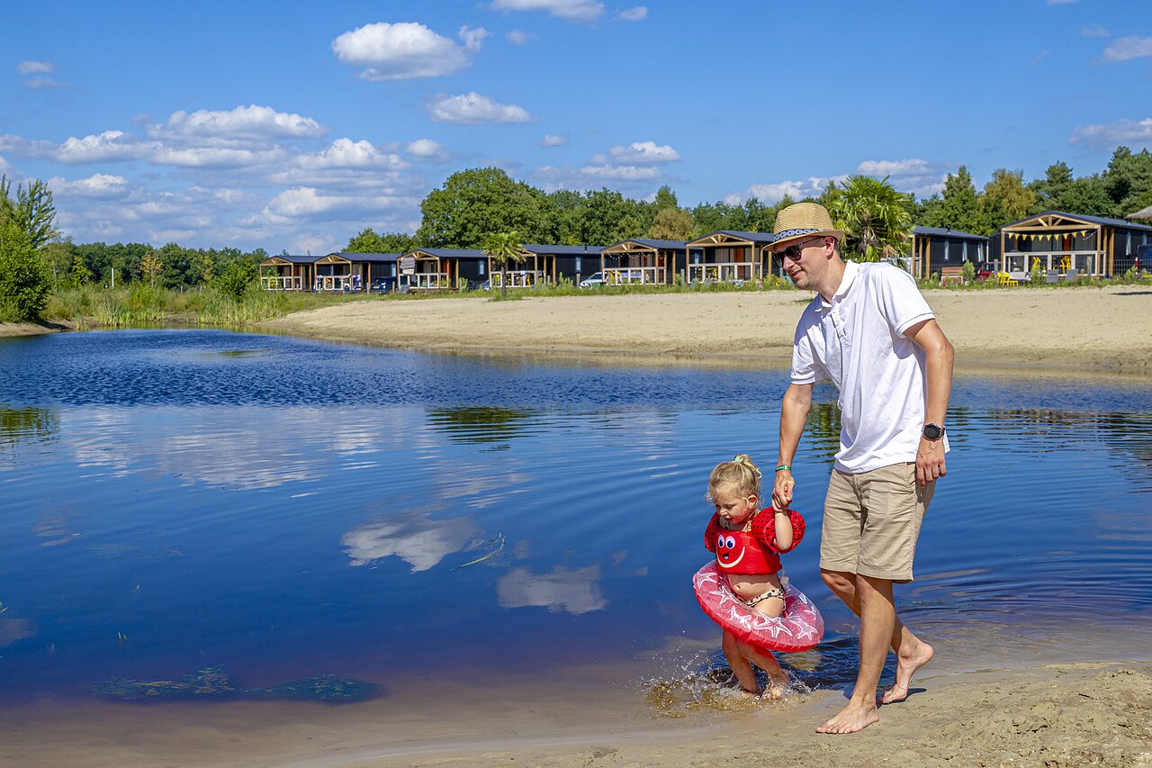 P�re et enfant dans le lac, plage et h�bergements au camping CAPFUN De Belten � Rheeze.