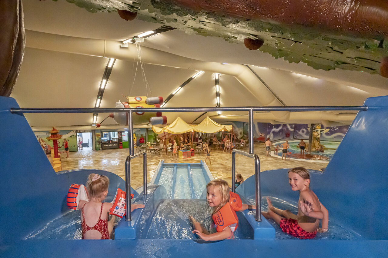 Enfants s'amusant sur le toboggan aquatique int�rieur au camping CAPFUN De Bongerd � Tuitjenhorn.