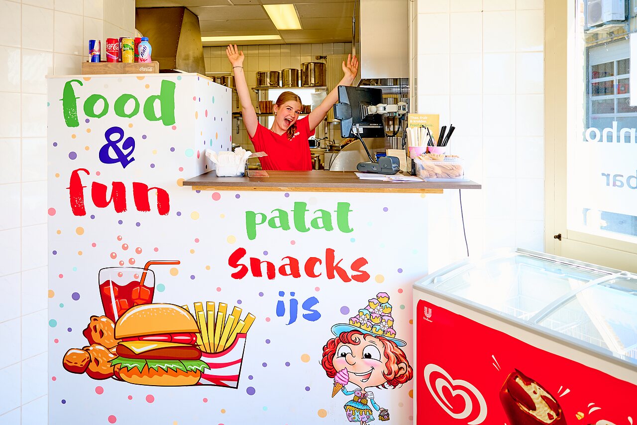 Kleurrijke snackbar balie met lachende medewerkster, friet en ijs op camping CAPFUN De Eikenhof in Paasloo/Oldemarkt.