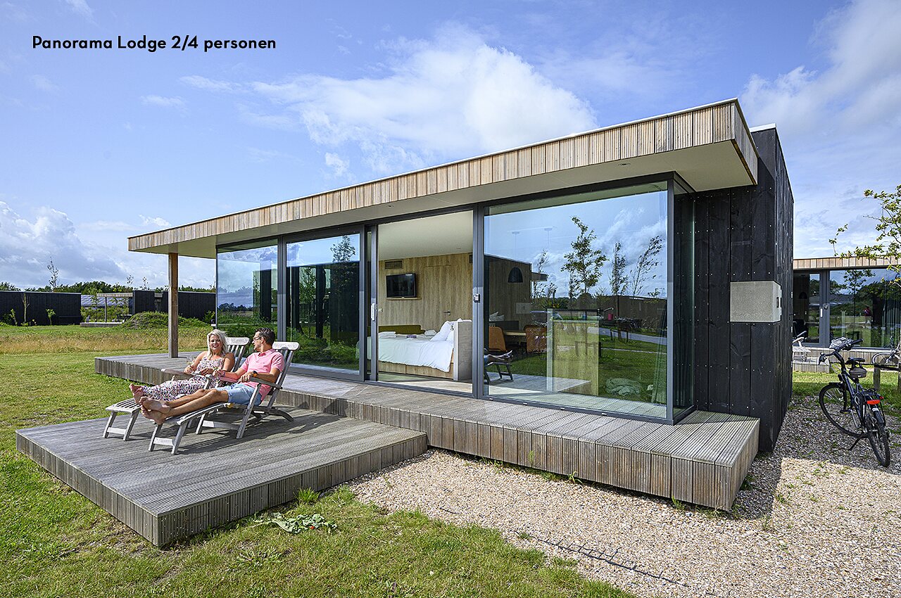 Lodge moderne avec terrasse et couple relaxant au camping CAPFUN De Pekelinge � Oostkapelle.