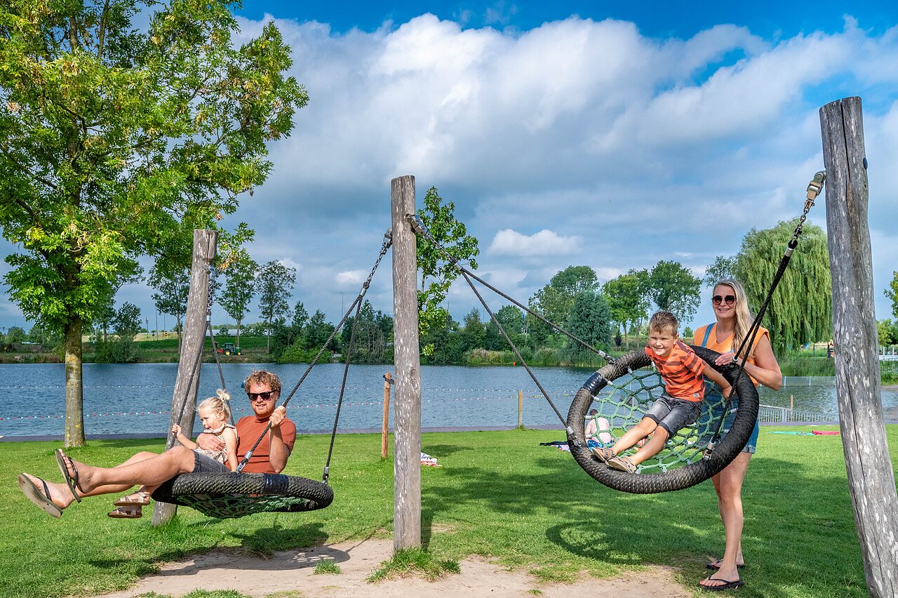Famille profitant des balan�oires g�antes pr�s du lac au camping CAPFUN De Rotonde � Enspijk.