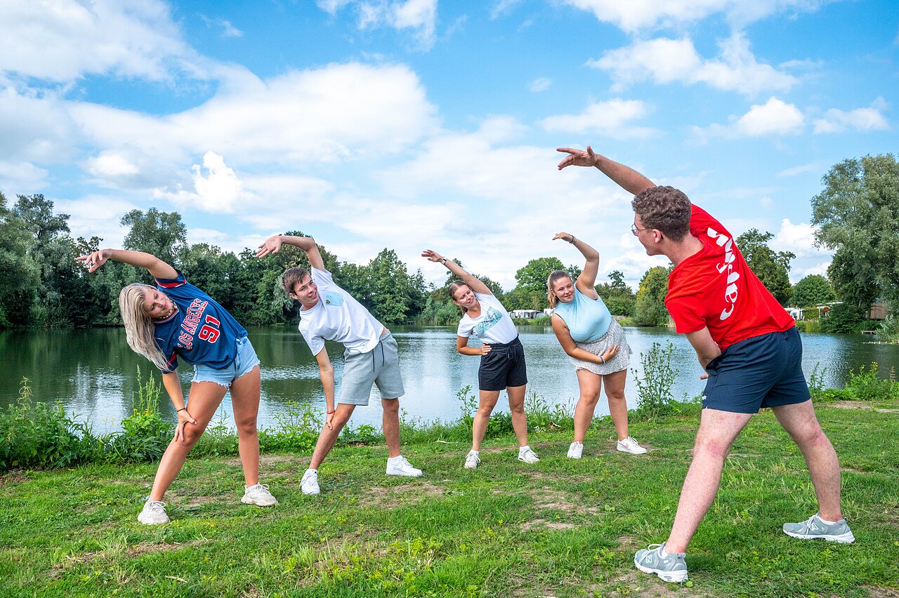 Groupe de jeunes faisant du stretching en plein air pr�s d'un lac au camping CAPFUN De Rotonde � Enspijk.