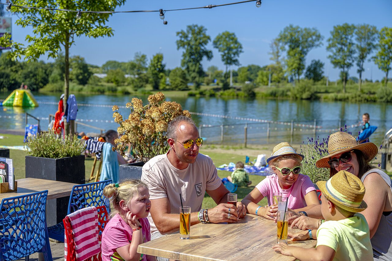 Famille d�jeunant en terrasse, activit�s nautiques sur le lac au camping CAPFUN De Rotonde � Enspijk.