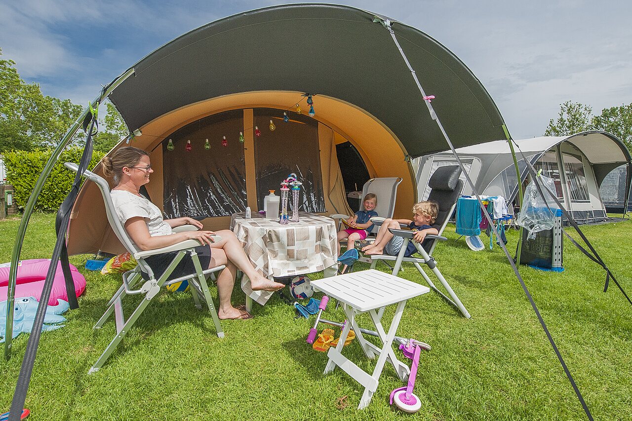 Famille profitant d'un emplacement de camping avec tente au CAPFUN De Rotonde.