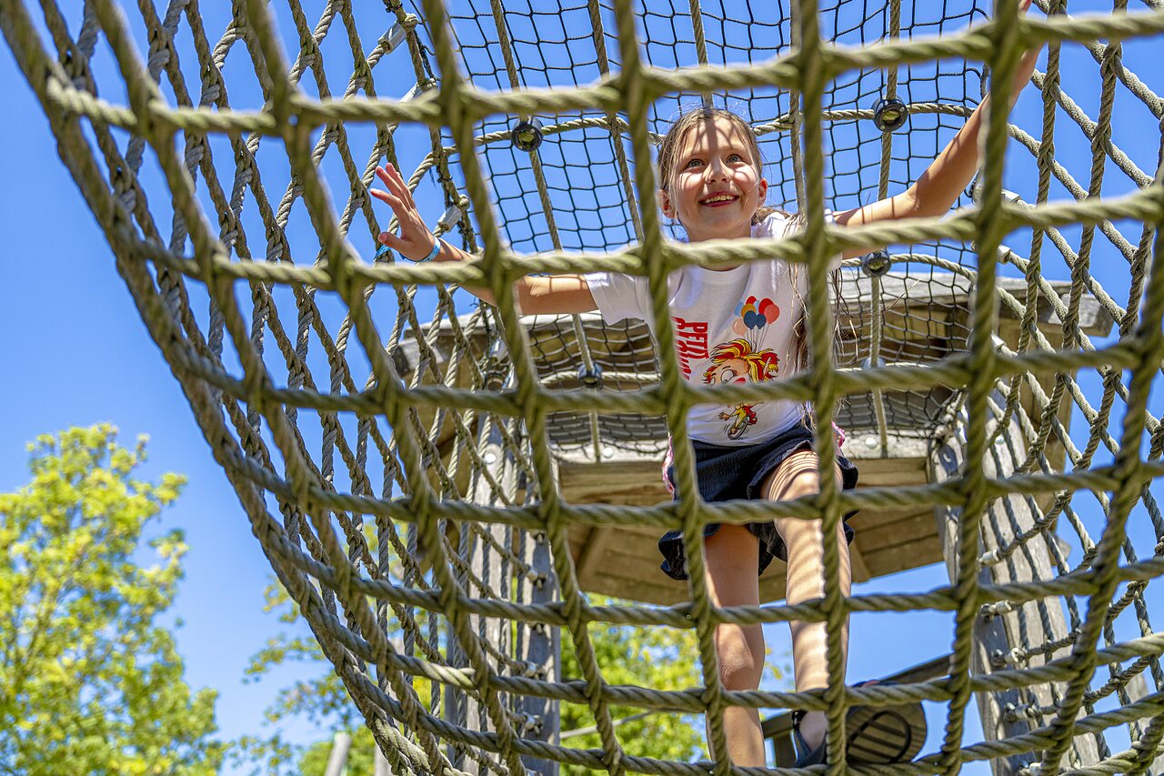 Enfant souriant sur structure d'escalade en filet au camping CAPFUN De Rotonde � Enspijk