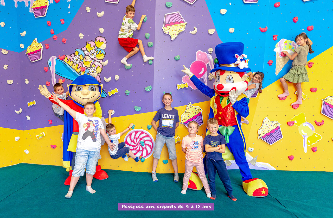 Enfants grimpant mur d'escalade int�rieur avec mascottes au camping CAPFUN Dune Fleurie (80).
