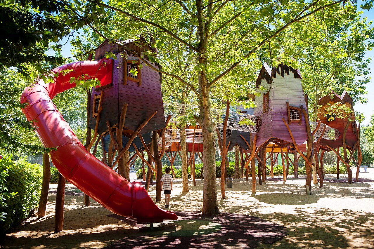 Aire de jeux avec cabanes perch�es, toboggan rouge au camping CAPFUN Duravel � Duravel (46).