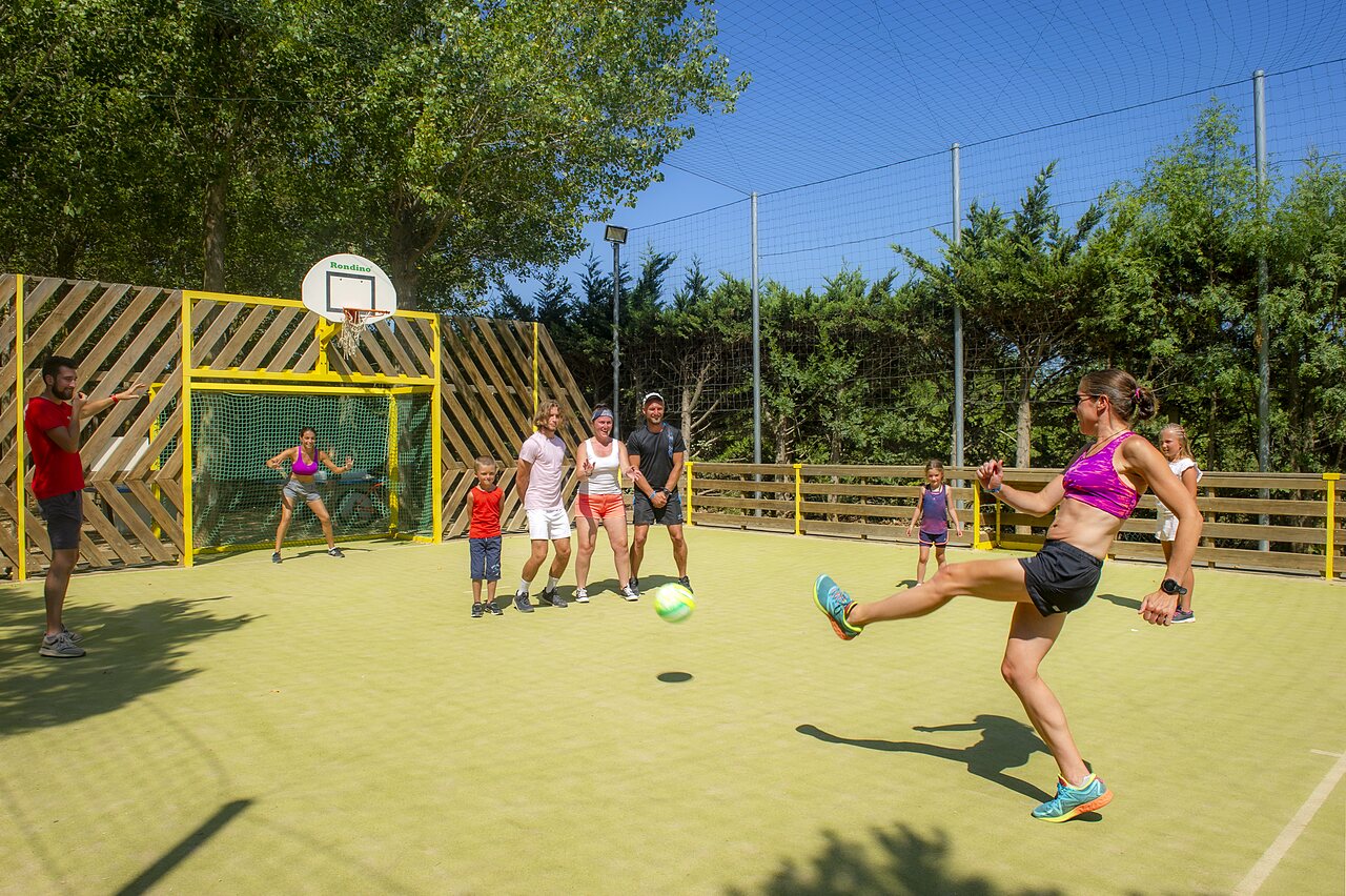 Terrain multisport avec adultes et enfants jouant au football au camping CAPFUN Emeraude � Portiragnes (34).