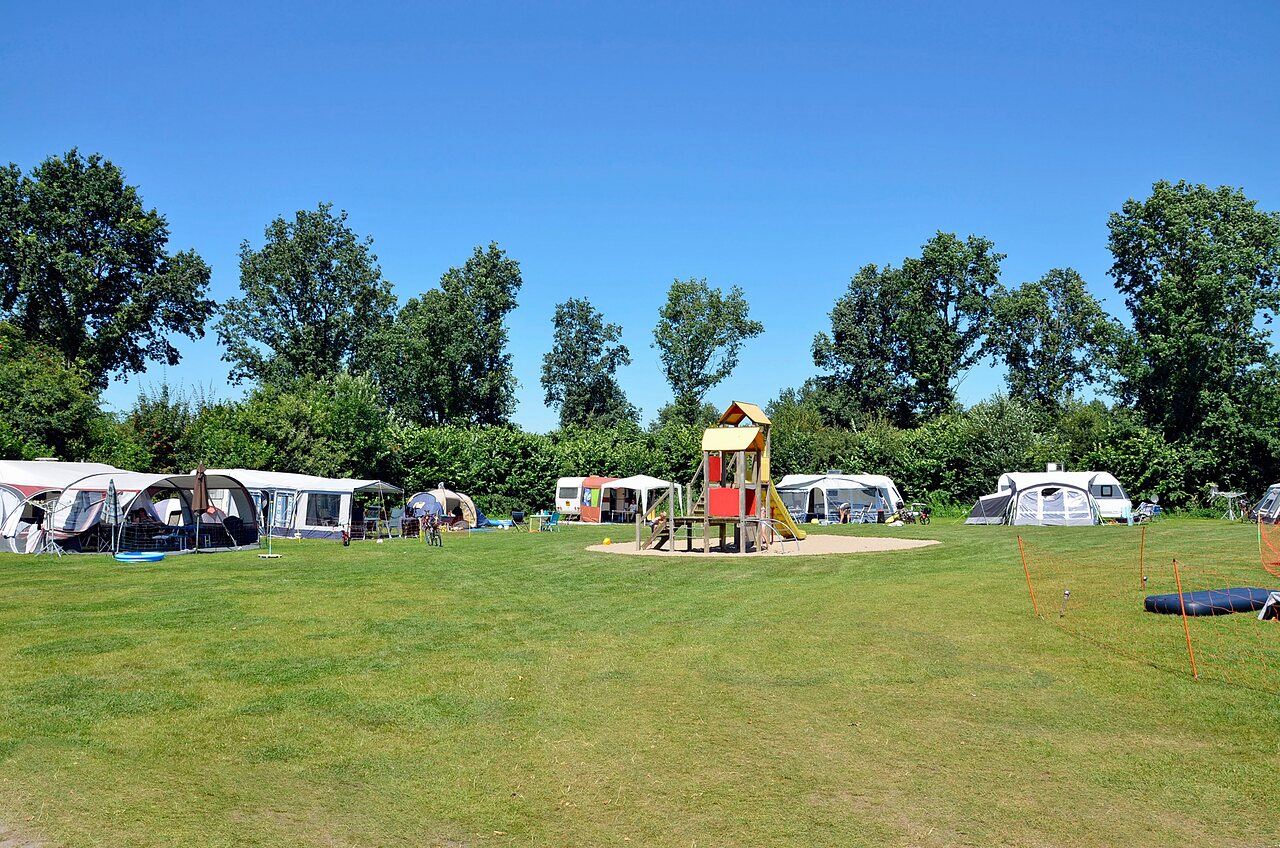 Emplacements de camping verdoyants avec aire de jeux et caravanes au camping CAPFUN Erkemederstrand � Zeewolde.