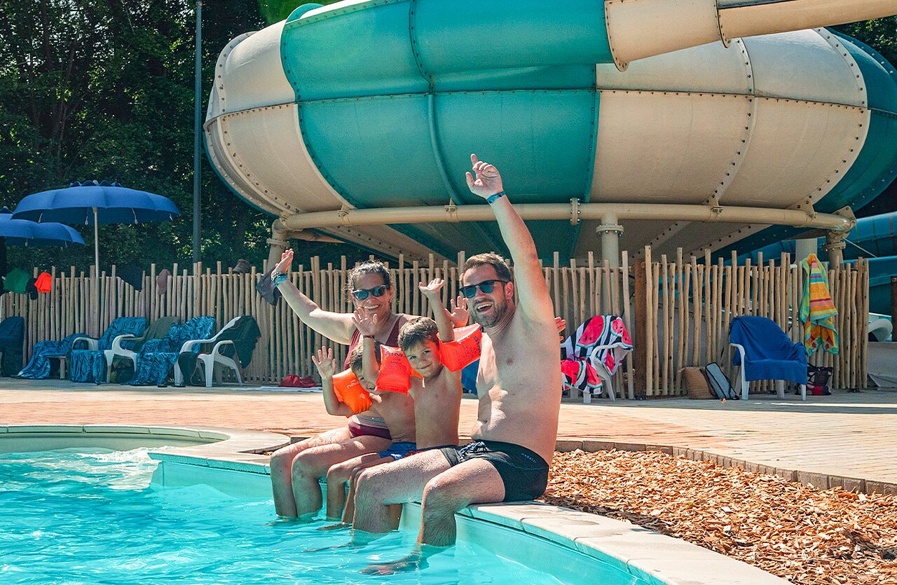 Famille souriante, piscine et toboggan au camping VAGUES OCEANES Lac d'Erstein (67).