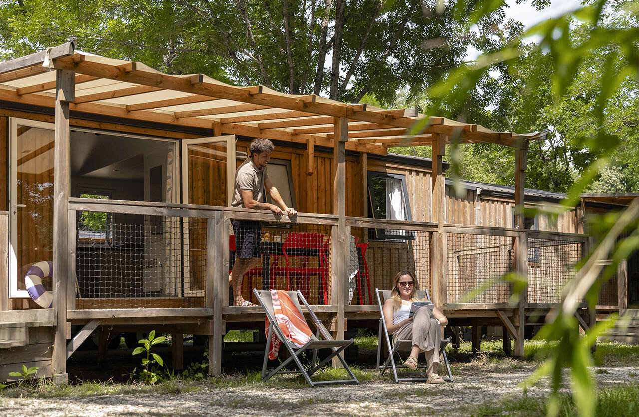 Mobile home moderne avec terrasse en bois et couple relaxant au camping CLICOCHIC Filament � Thoiras (30).