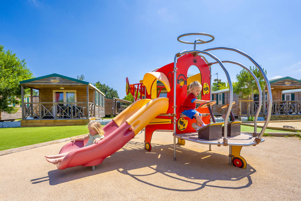 Enfants sur aire de jeux avec toboggan, au camping CAPFUN Fleur de Camargue (30).