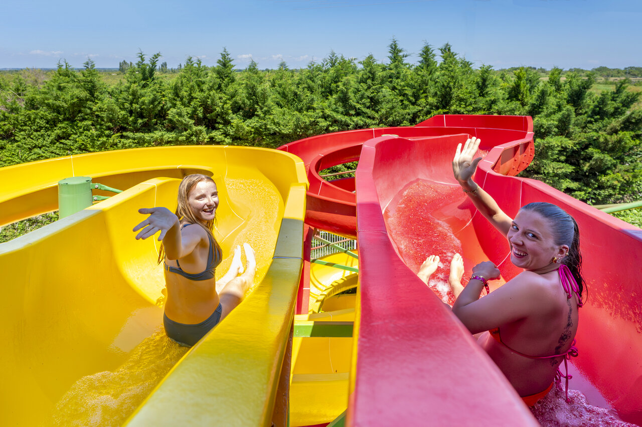 Deux femmes souriantes sur des toboggans aquatiques au camping CAPFUN Fleur de Camargue � Saint-Laurent-d Aigouze.