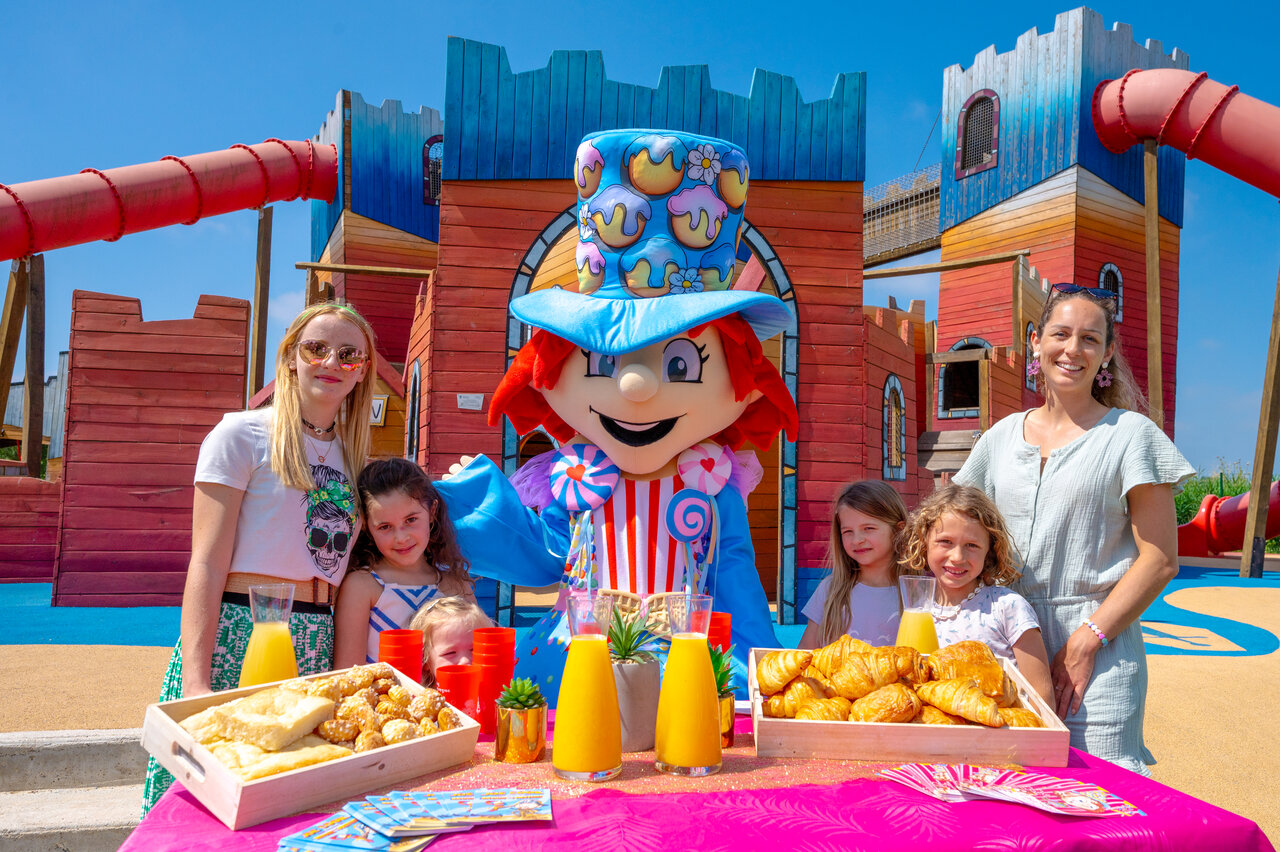 Mascotte et enfants profitant d'un petit-d�jeuner festif devant l'aire de jeux au camping CAPFUN Fleur de Camargue � Saint-Laurent-d Aigouze (30).