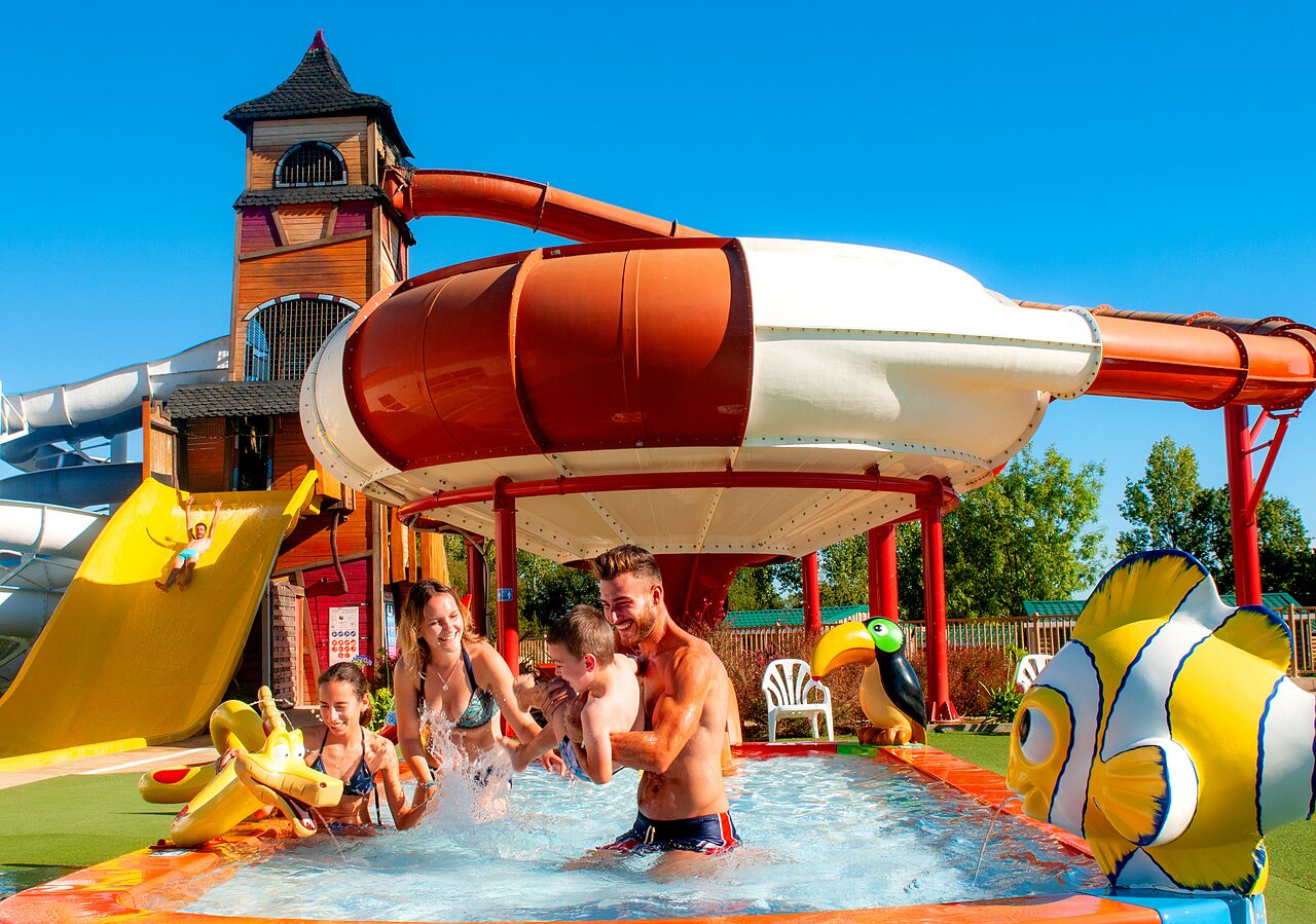 Famille s'amusant dans l'aire de jeux aquatique avec toboggans au camping CAPFUN Forges � Avrille (85).
