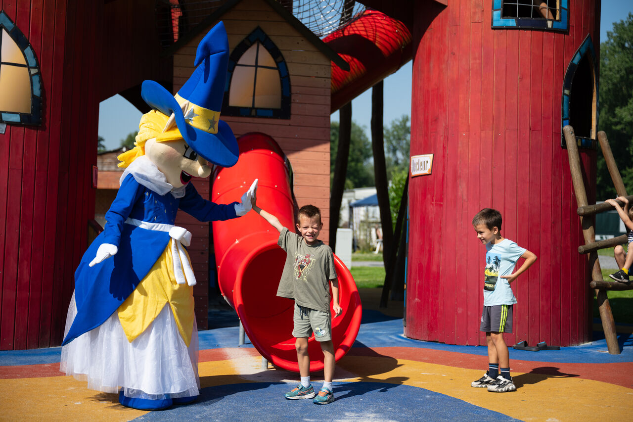 Mascotte et enfants jouant sur l'aire de jeux avec toboggan au camping CAPFUN Fort Bedmar � Sint-Gillis-Waas.