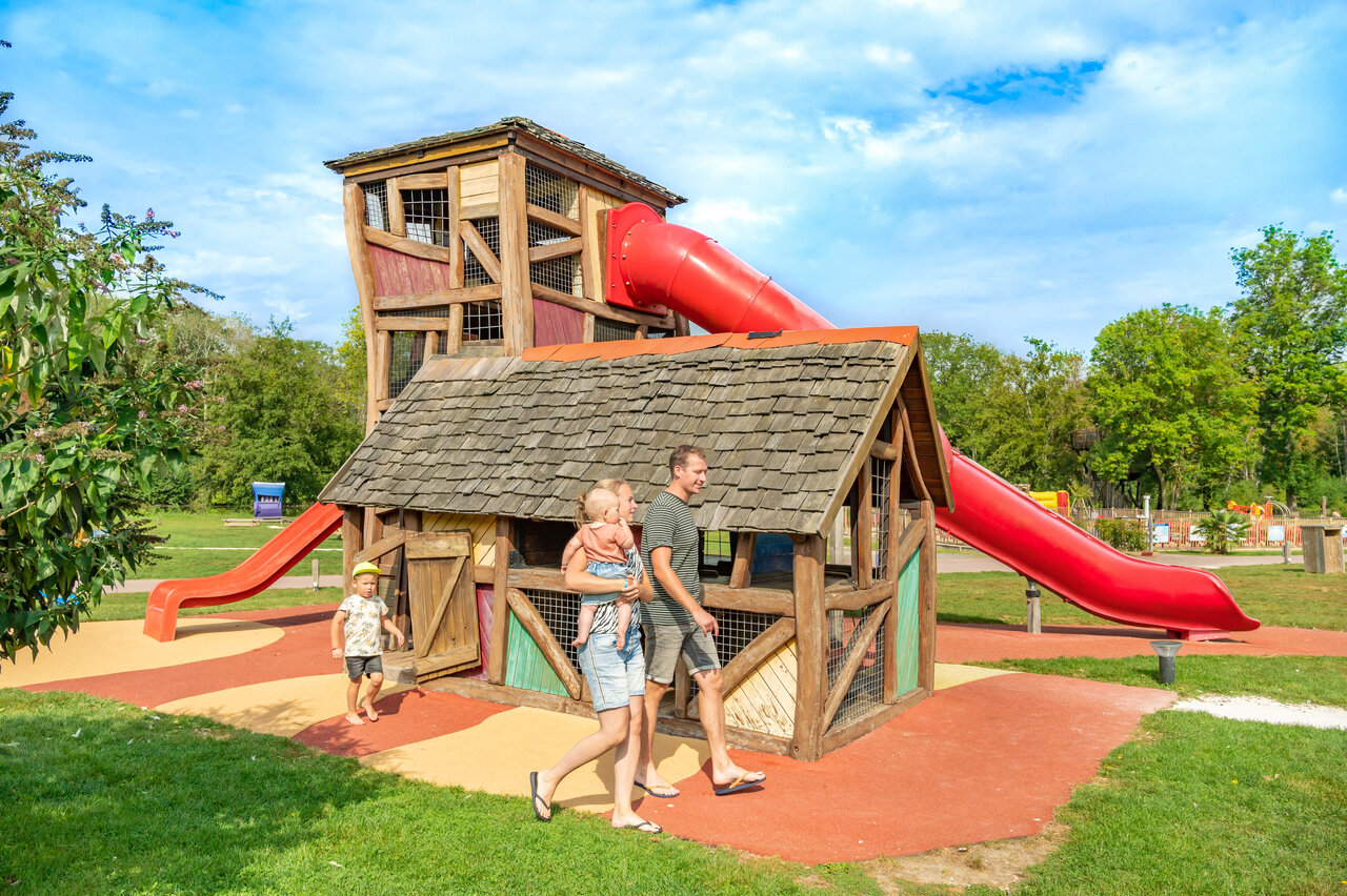 Large wooden play structure with red slides at CAPFUN Fredland campsite in Tournan en Brie (77).
