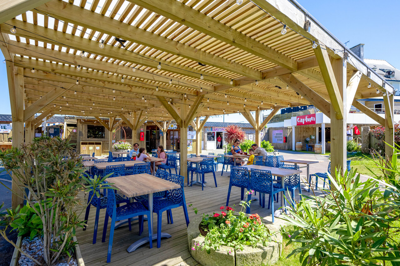 Terrasse ombrag�e du restaurant avec tables bleues au camping CAPFUN Grand Large � FOUESNANT (29).