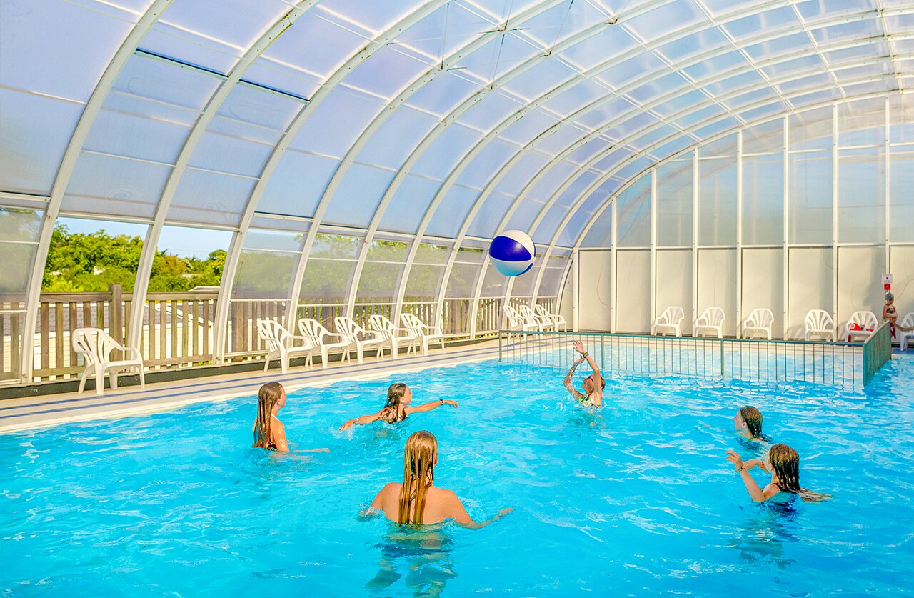 Piscine couverte, enfants jouant au ballon au camping VAGUES OCEANES Grosses Pierres.