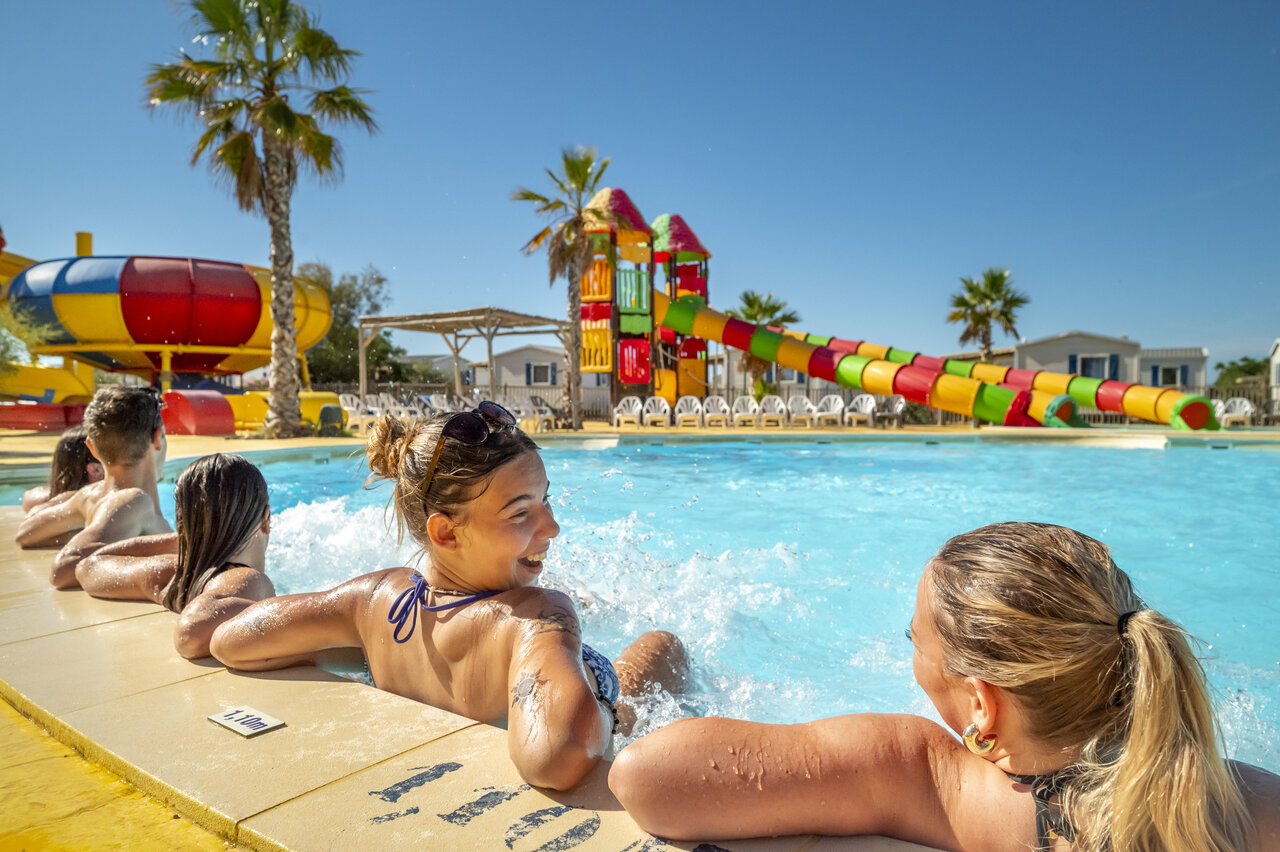 Piscine ext�rieure avec toboggans aquatiques color�s et baigneurs au camping VAGUES OCEANES Hamacs � Fleury (11).