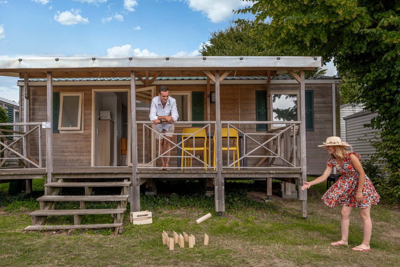 Mobil-home en bois avec terrasse, couple jouant au M�lkky au camping CLICOCHIC Haras de Deauville � Touques.