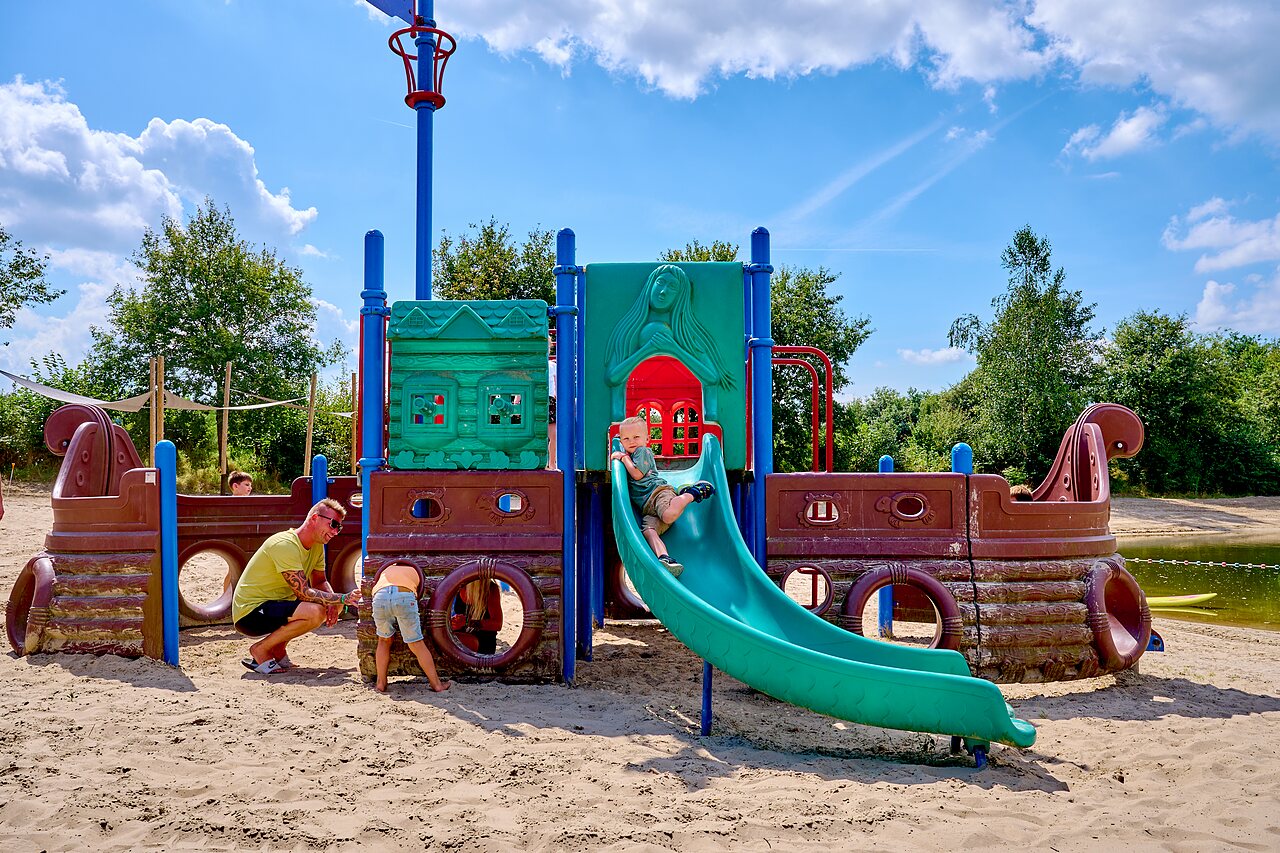 Enfant souriant dans tunnel en filet sur aire de jeux au CAPFUN Heino.