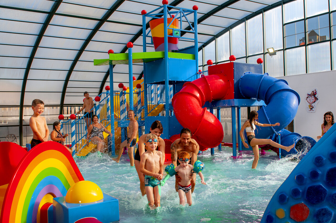 Espace aquatique couvert avec toboggans color�s et jeux d'eau au camping CAPFUN Hirondelle � Oteppe.