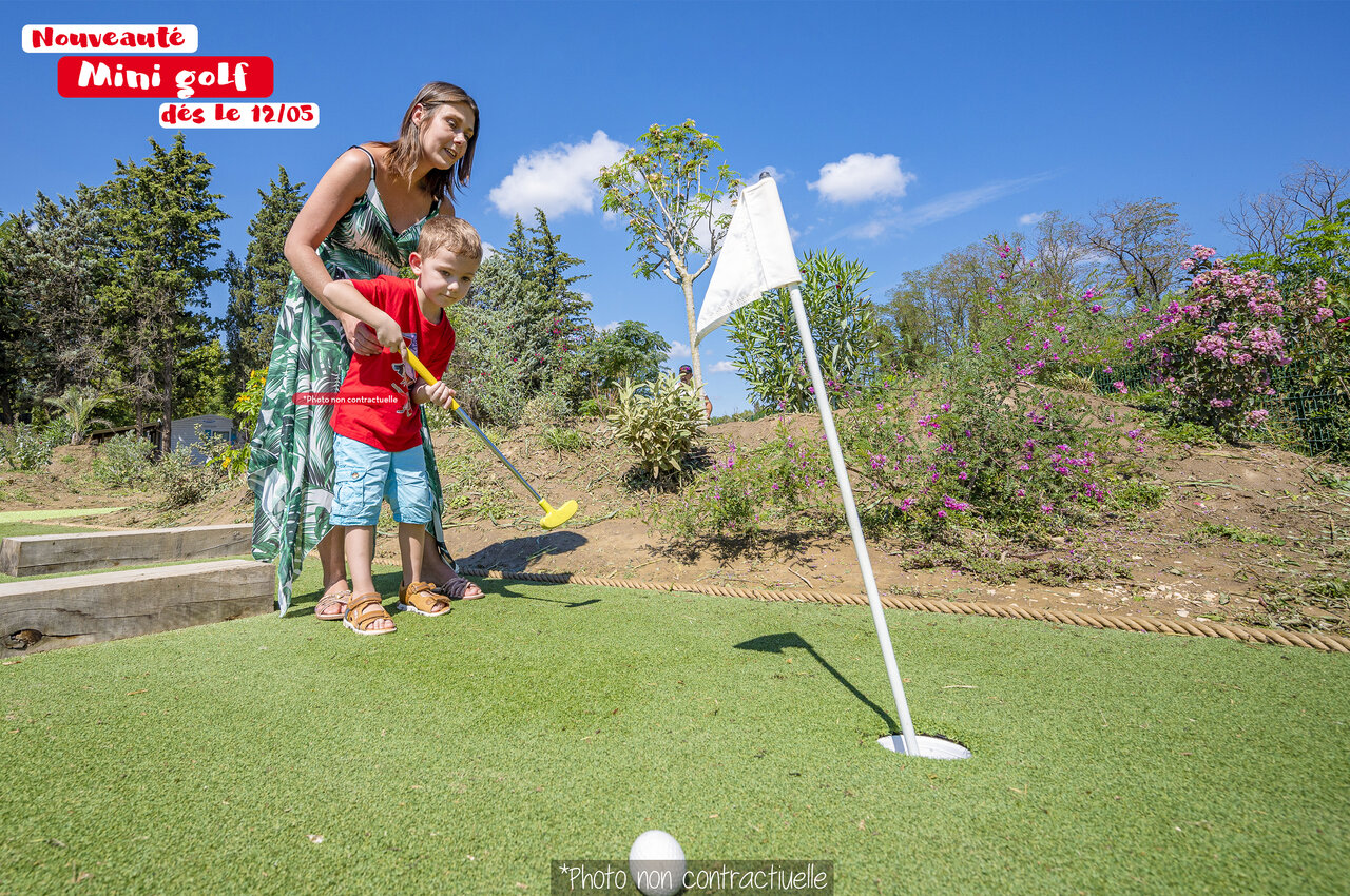 Enfant et femme jouent au mini-golf au camping CAPFUN Huttes � Saint-Denis d'Ol�ron.