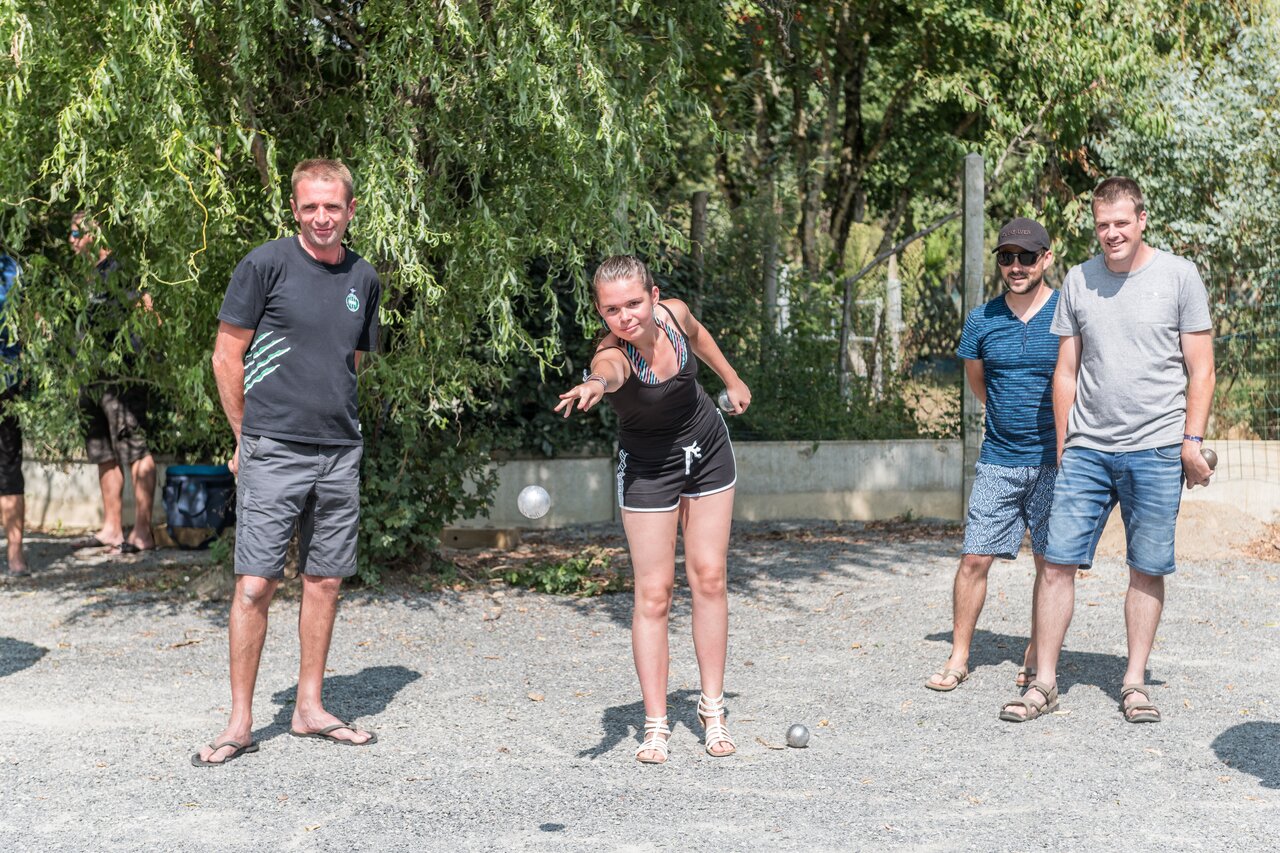 Jeunes et adultes jouant � la p�tanque sur un terrain, au camping CAPFUN Huttes � Saint-Denis d'Ol�ron (17).