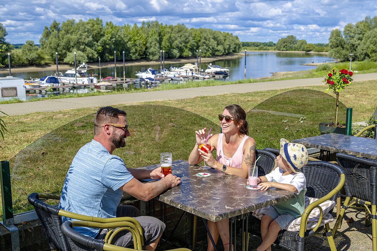 Famille souriante buvant des verres en terrasse pr�s d'un port de plaisance au camping CAPFUN IJsselstrand � Doesburg.