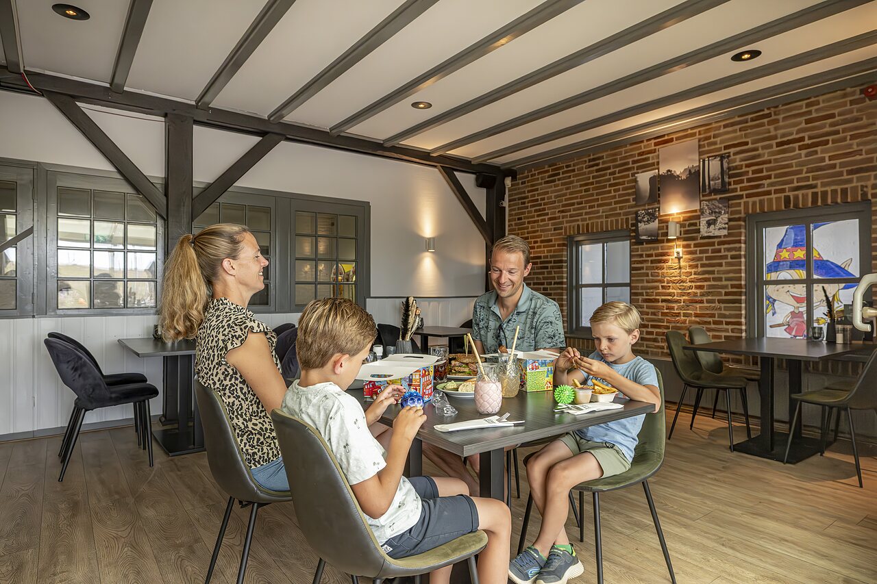 Restaurant familial avec enfants jouant � table au camping CAPFUN IJsselstrand � Doesburg.