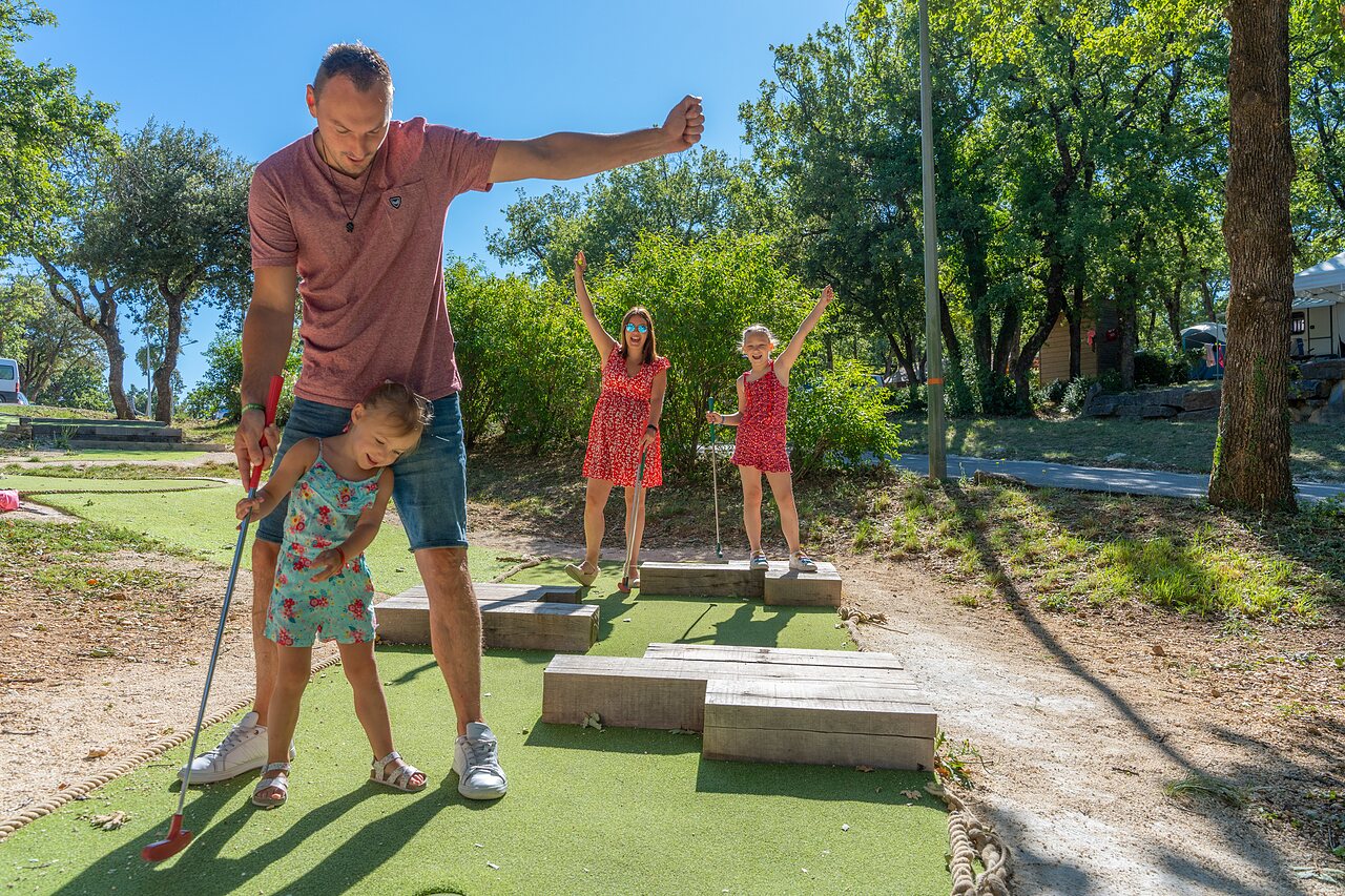 Famille jouant au mini-golf sur un parcours ext�rieur au camping CAPFUN Imbours � LARNAS (07).
