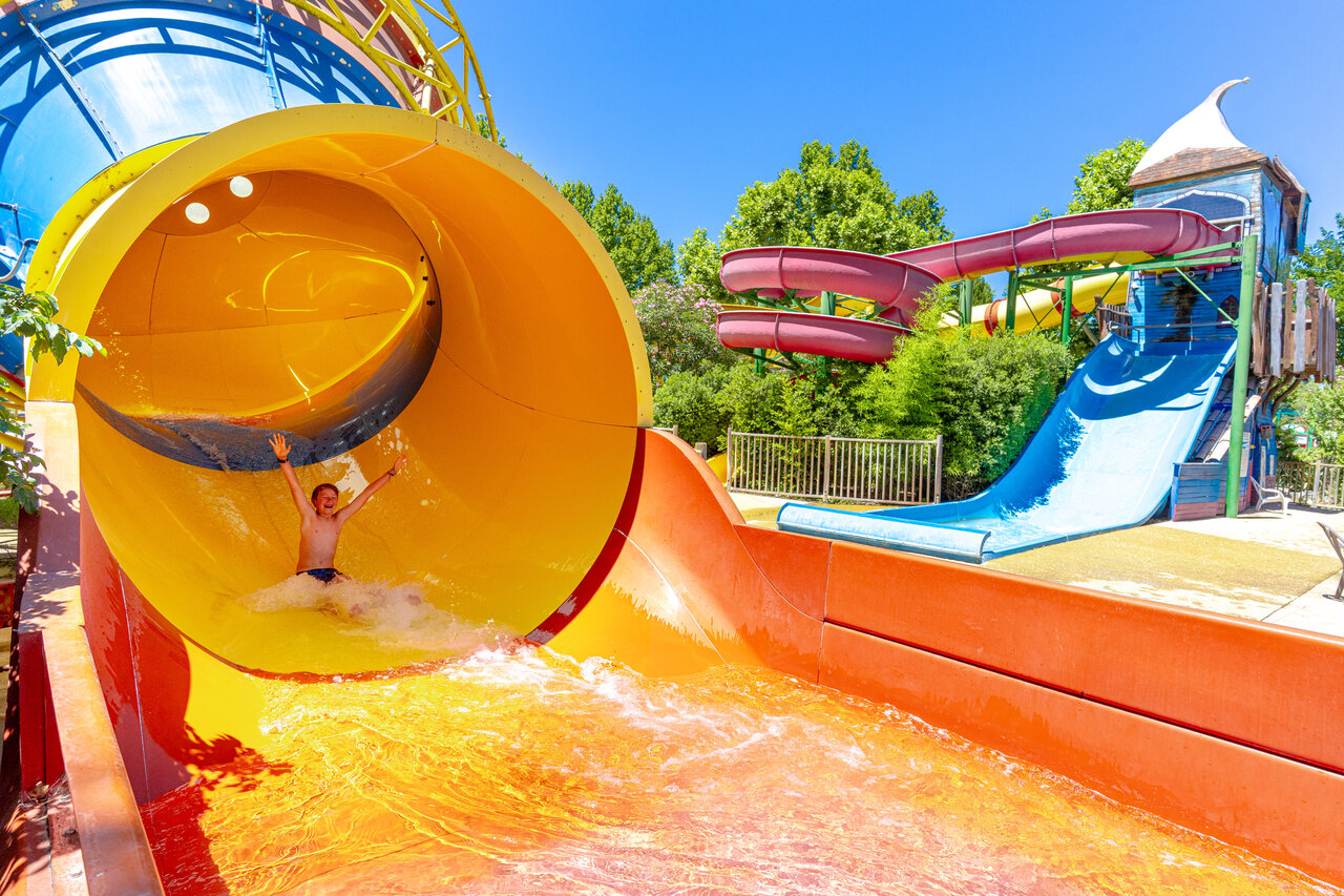 Enfant souriant descendant un toboggan aquatique g�ant au camping CAPFUN Jantou � LE THOR (84).