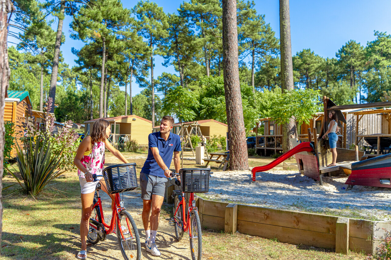 Couple avec v�los et aire de jeux enfants au camping CAPFUN Landisland � Moliets-et-Maa.